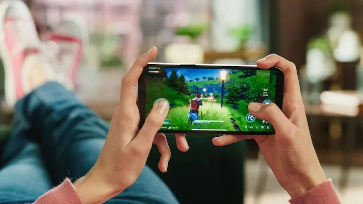 A player holding a smartphone sideways, playing a 3D mobile game